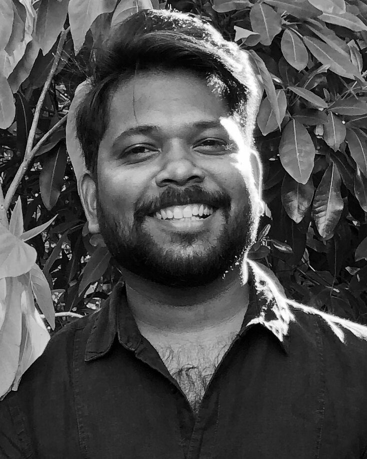 Udhaya Kumar, smiling, in front of leafy trees